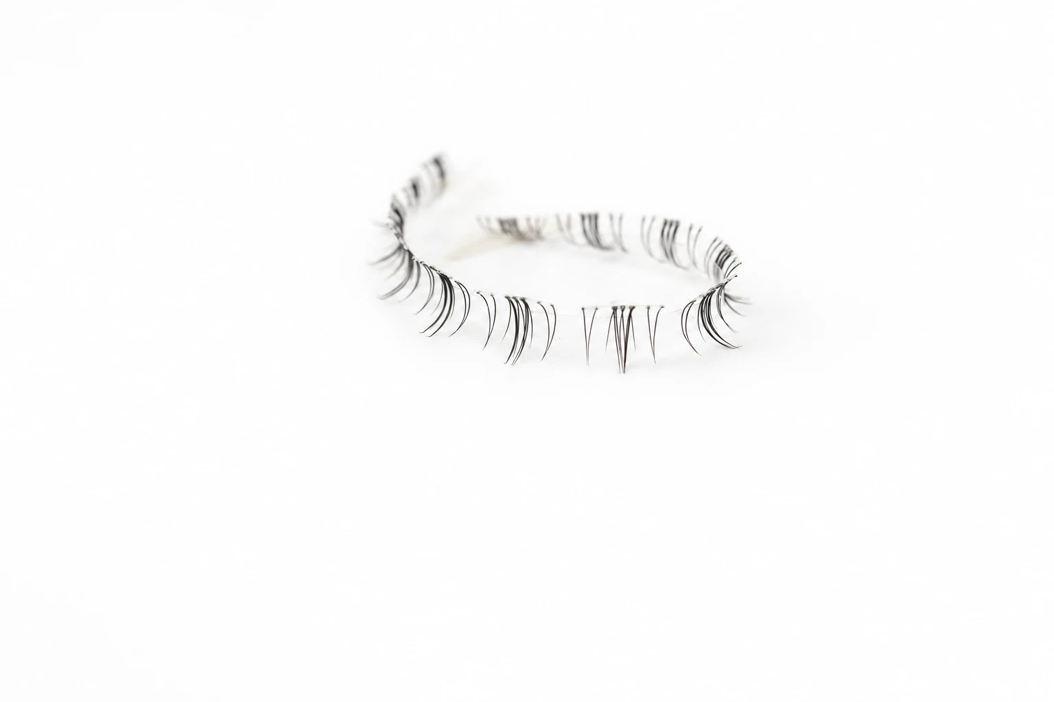 AI-assisted presentation of sparse lower-lash segments on a curved clear carrier, based on a supplied product photograph